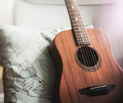 acoustic guitar sitting upright against a pillow on a couch
